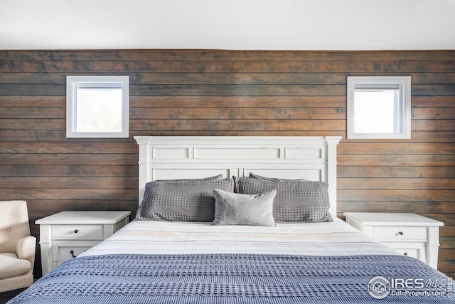 bedroom with multiple windows and wood walls
