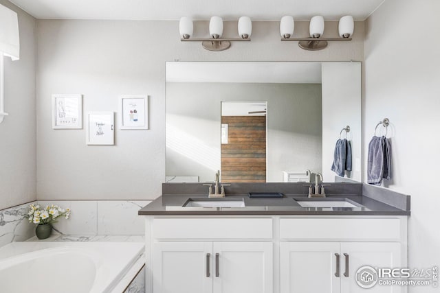 bathroom featuring double vanity, a bath, and a sink
