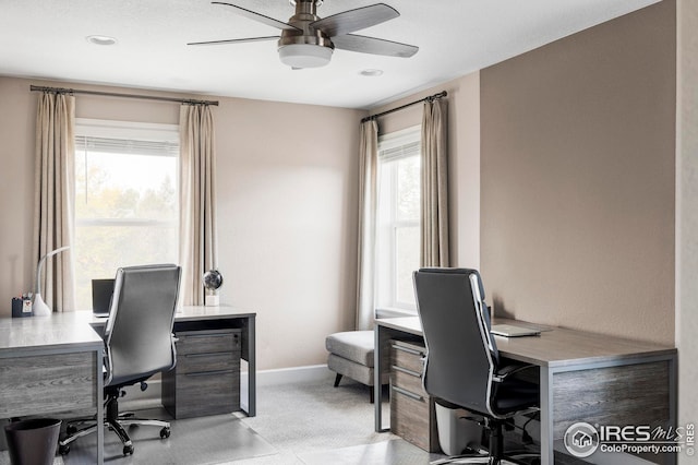 office space featuring baseboards, light colored carpet, and a ceiling fan