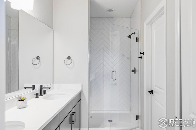 bathroom with double vanity, a stall shower, and a sink