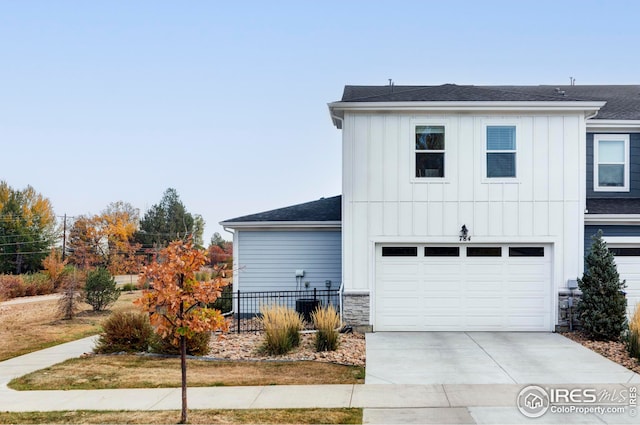exterior space featuring stone siding, fence, board and batten siding, concrete driveway, and a garage