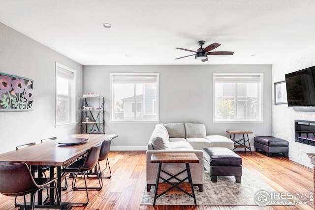 living room with light wood-type flooring, baseboards, and a ceiling fan