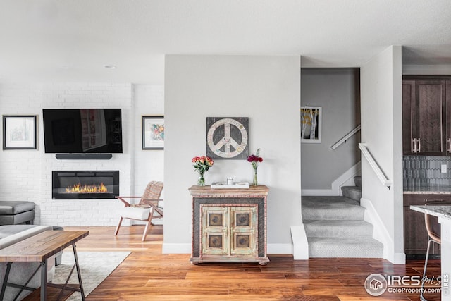 living room with stairway, baseboards, wood finished floors, and a fireplace