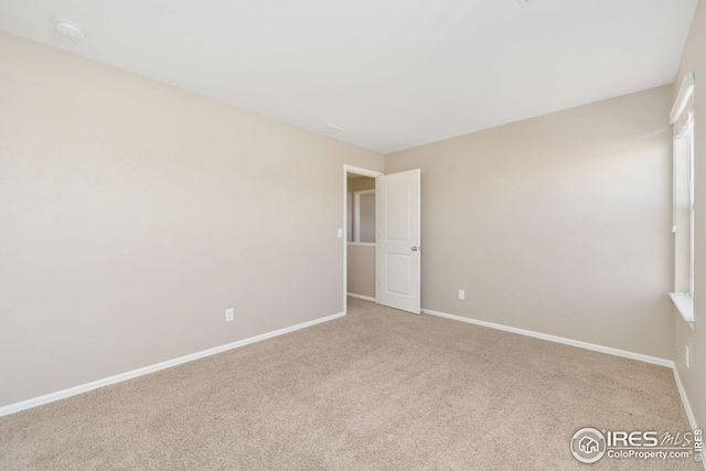 spare room featuring carpet and baseboards