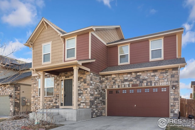 view of front of house with concrete driveway, stone siding, a garage, and fence
