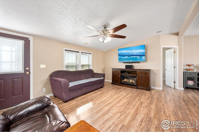 living room with a textured ceiling, vaulted ceiling, wood finished floors, and ceiling fan