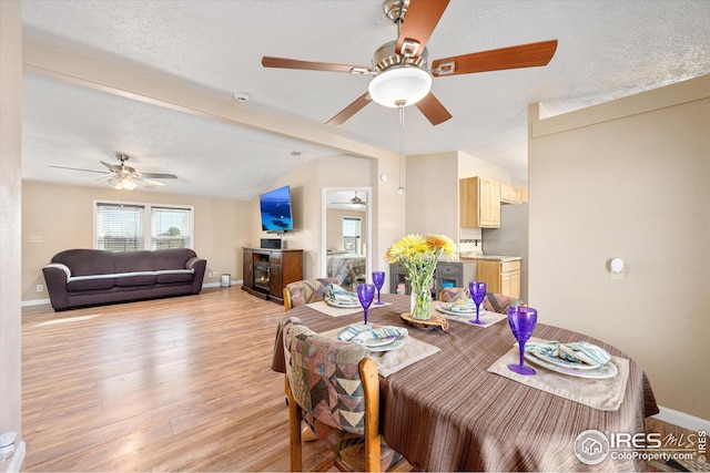 dining space featuring a textured ceiling, baseboards, light wood finished floors, and ceiling fan
