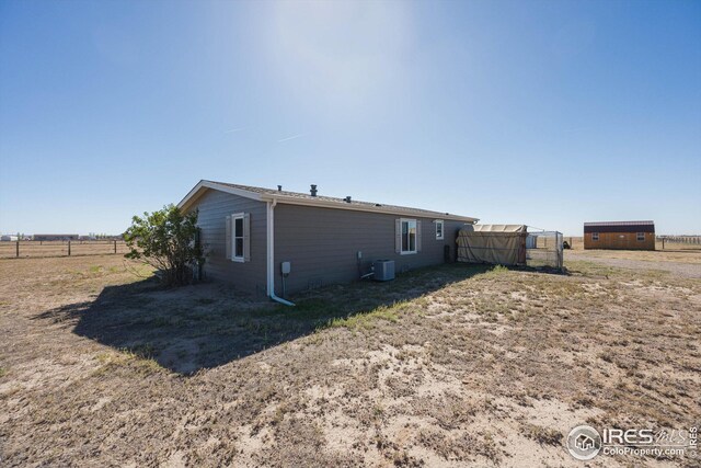 rear view of house featuring an outbuilding, fence, and central AC