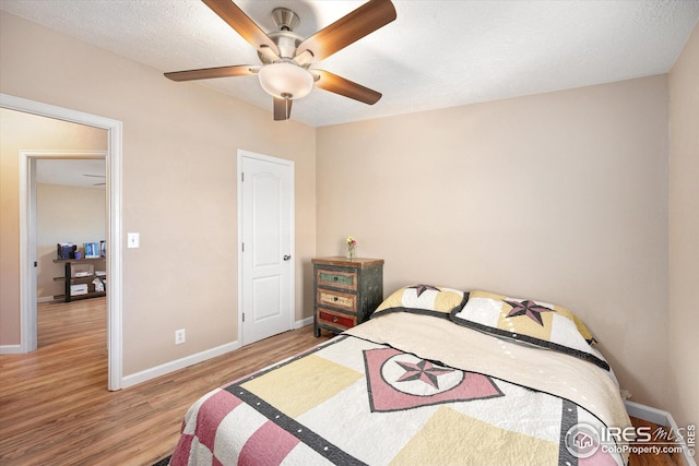 bedroom featuring baseboards, wood finished floors, and a ceiling fan