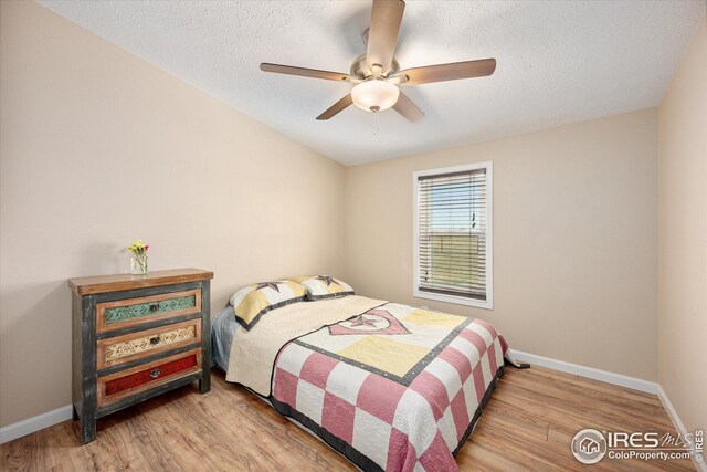 bedroom with wood finished floors, baseboards, and a textured ceiling