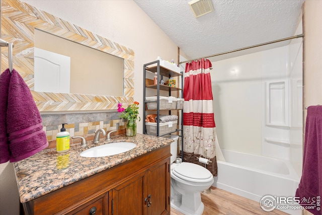 bathroom with visible vents, toilet, a textured ceiling, wood finished floors, and vanity
