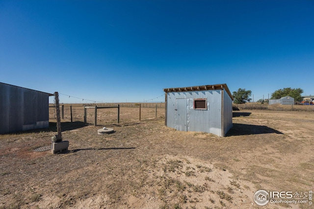 view of yard featuring a storage shed, an outdoor structure, and fence