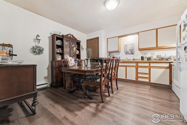 dining room with baseboard heating, a textured ceiling, and light wood-type flooring