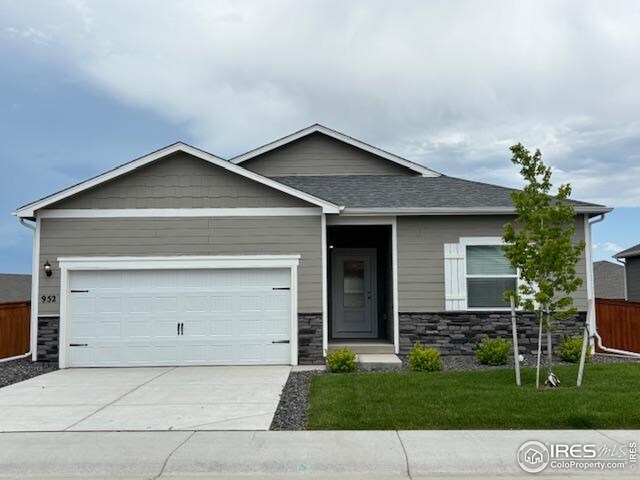 952 Cascade Falls St, Severance, CO 80550 - view of front of house with stone siding, driveway, an attached garage, and roof with shingles