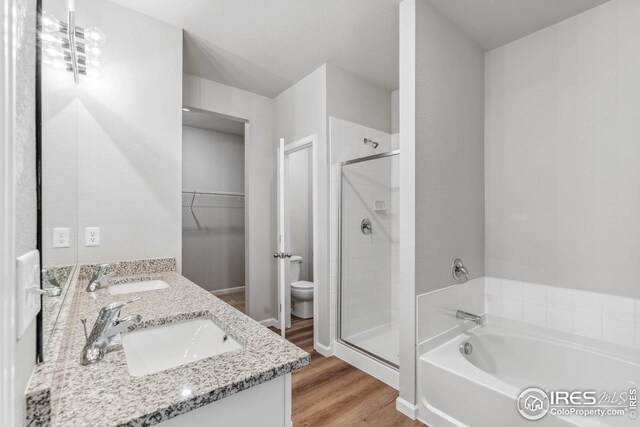 952 Cascade Falls St, Severance, CO 80550 - bathroom featuring a shower stall, a garden tub, double vanity, wood finished floors, and a spacious closet