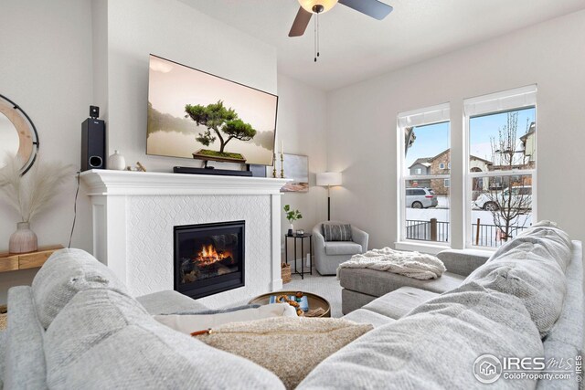 carpeted living area with a tile fireplace and ceiling fan