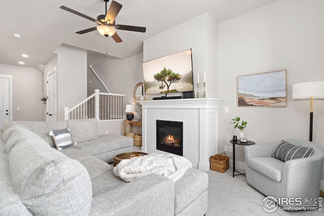 carpeted living area featuring baseboards, stairs, recessed lighting, a glass covered fireplace, and a ceiling fan