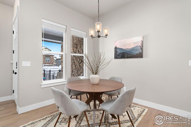 dining room with light wood finished floors, a notable chandelier, and baseboards