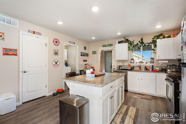 4216 Yellowbells Dr, Evans, CO 80620 - kitchen featuring appliances with stainless steel finishes, white cabinetry, wood finished floors, a center island, and recessed lighting