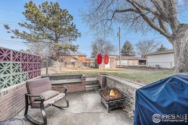 view of patio / terrace with an outdoor fire pit, area for grilling, a fenced backyard, an outdoor structure, and a storage shed