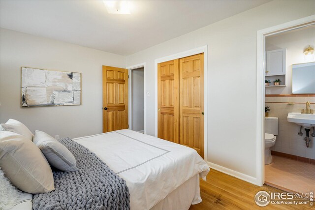 169 Emerald St, Broomfield, CO 80020 - bedroom featuring a sink, tile walls, a closet, wood finished floors, and ensuite bath