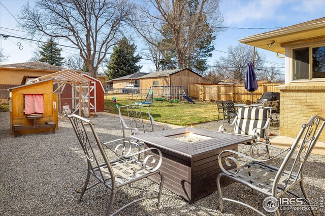 169 Emerald St, Broomfield, CO 80020 - view of patio with fence, a fire pit, a shed, an outbuilding, and a playground