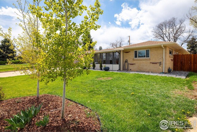 169 Emerald St, Broomfield, CO 80020 - rear view of house with fence, a sunroom, a yard, and brick siding