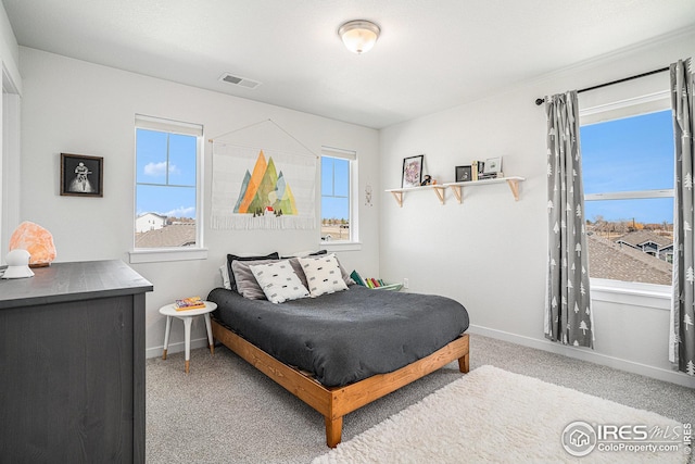 carpeted bedroom with visible vents, multiple windows, and baseboards