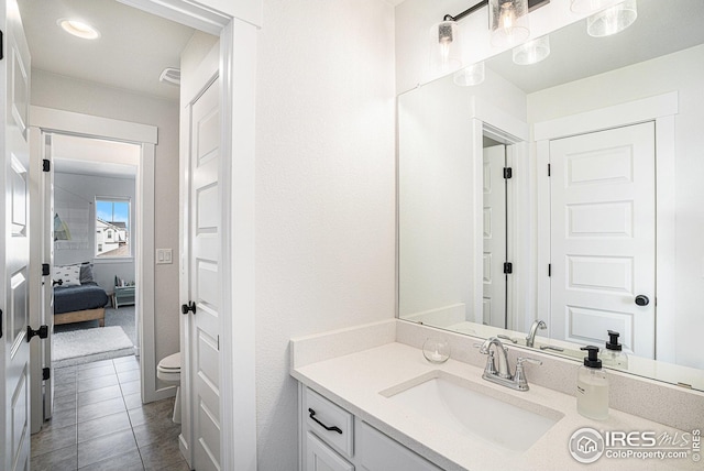 bathroom with toilet, vanity, and tile patterned flooring