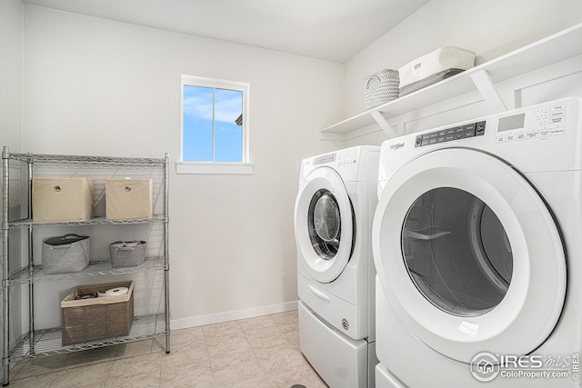 clothes washing area featuring washer and dryer, baseboards, and laundry area