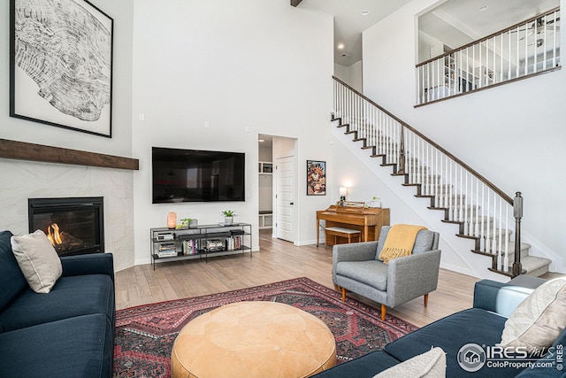 living room featuring a high end fireplace, stairs, baseboards, and wood finished floors