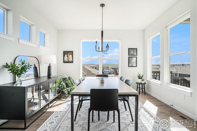 dining area featuring baseboards, an inviting chandelier, and wood finished floors