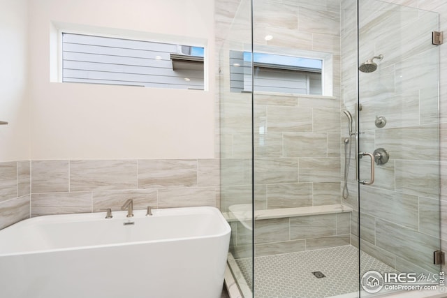bathroom with a stall shower and a freestanding bath