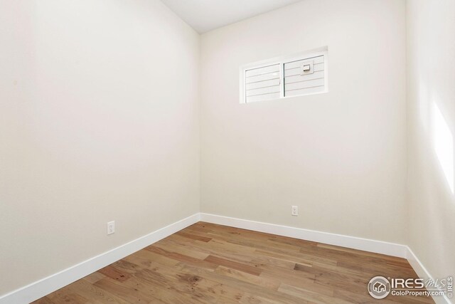 spare room featuring baseboards and wood finished floors