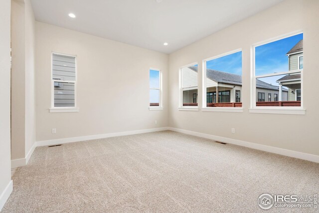carpeted empty room featuring baseboards, visible vents, and recessed lighting