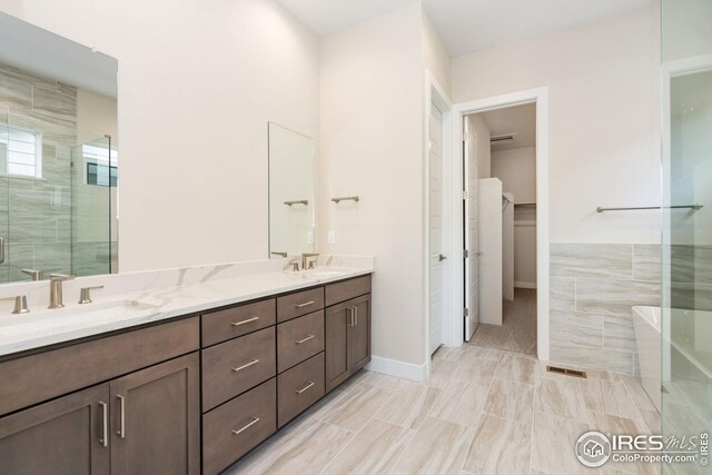 full bath with a freestanding tub, double vanity, a sink, and a stall shower