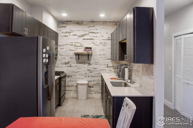 kitchen with a sink, range with gas cooktop, stainless steel fridge with ice dispenser, wallpapered walls, and light countertops