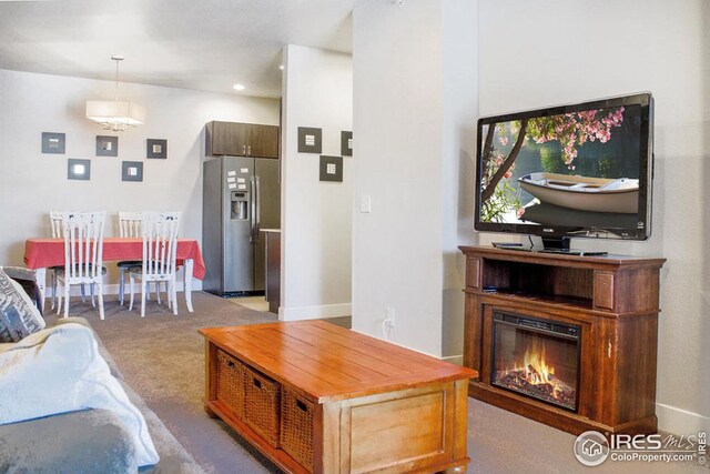 carpeted living area featuring baseboards and a glass covered fireplace