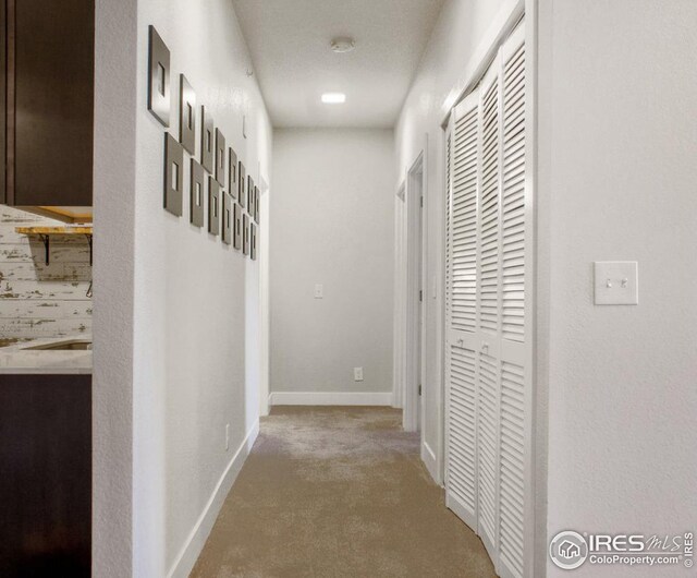 corridor featuring baseboards and carpet floors