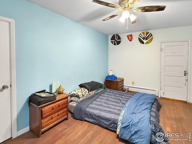 105 N Logan Ave, Haxtun, CO 80731 - bedroom featuring a baseboard heating unit, wood finished floors, ceiling fan, and baseboards