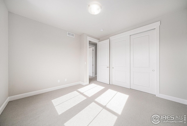 unfurnished bedroom featuring carpet floors, a closet, visible vents, and baseboards