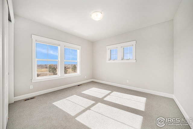 carpeted spare room featuring visible vents and baseboards