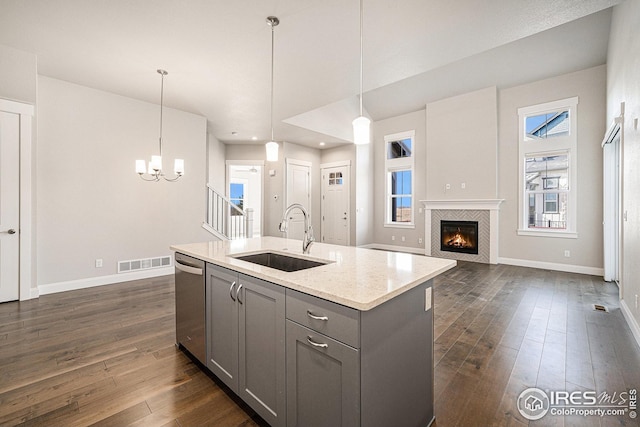 kitchen with stainless steel dishwasher, a sink, an inviting chandelier, gray cabinetry, and visible vents