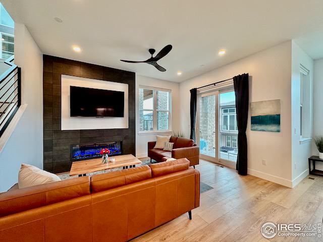 living area with recessed lighting, light wood-type flooring, baseboards, a large fireplace, and a ceiling fan