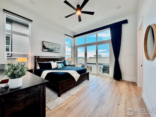 bedroom with baseboards, light wood-type flooring, a ceiling fan, and access to outside