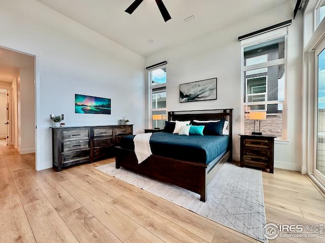 bedroom featuring light wood-style flooring, baseboards, multiple windows, and ceiling fan