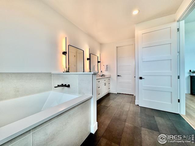 full bath featuring vanity and a garden tub