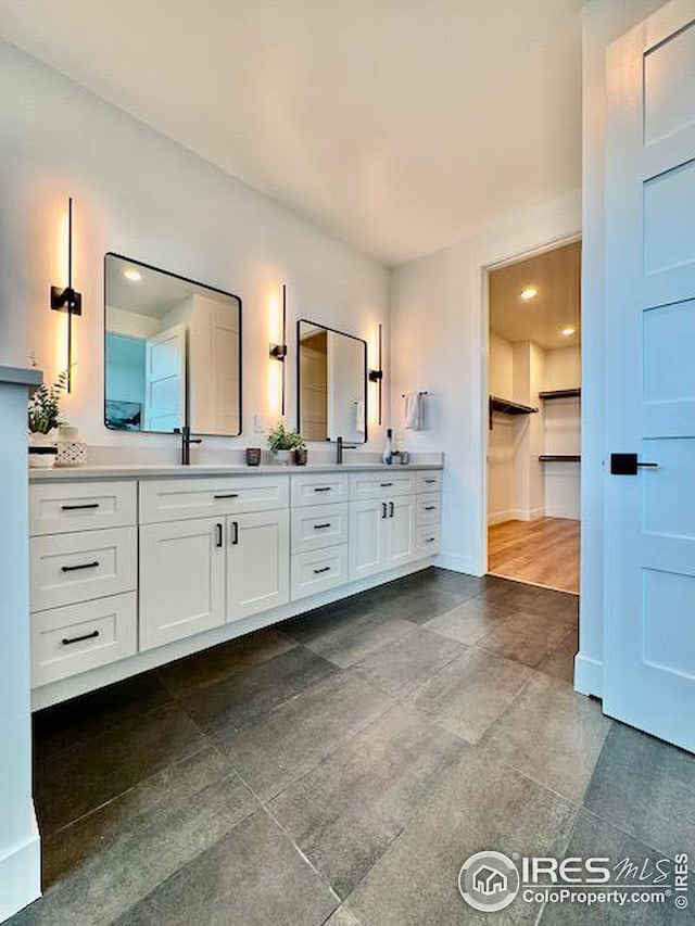 bathroom featuring baseboards, a spacious closet, and vanity