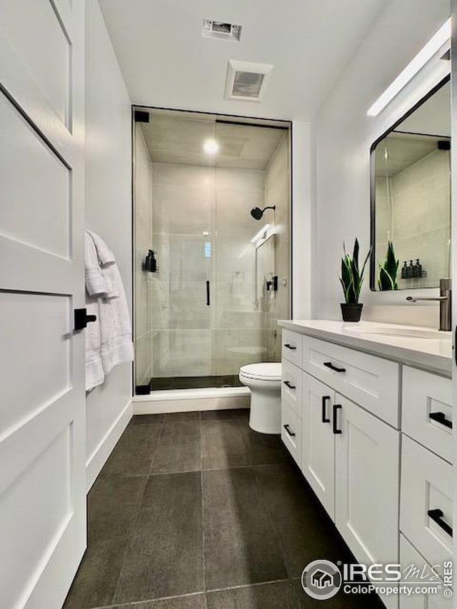 bathroom featuring visible vents, toilet, a stall shower, and vanity