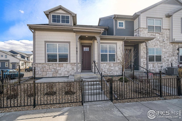 4191 Greenhorn Dr, Loveland, CO 80538 - view of front of house with central AC, a gate, stone siding, and a fenced front yard